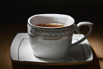 White cup of tea on a white saucer on bamboo napkin