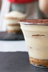 Handmade process of making an Italian tiramisu cake at home. The finished cake is on the background of another