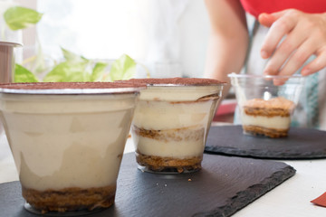 Handmade process of making an Italian tiramisu cake at home. Two ready cakes are on the background of uncooked one
