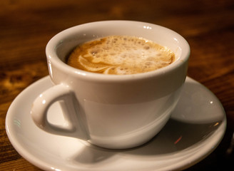 cup of coffee with cream on wooden background