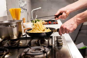 Cooking italian pasta in a pot in the kitchen, Chef preparing food, meal. Woman cook pulls out of the pan ready-made pasta fusilli
