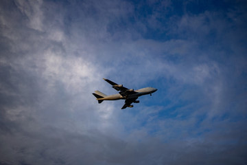 Airplane preparing for landing amongst clouds at sunset
