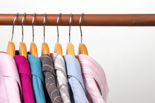 Different women's office classic shirts hang on a hanger for storing clothes. The choice of style of fashionable clothes