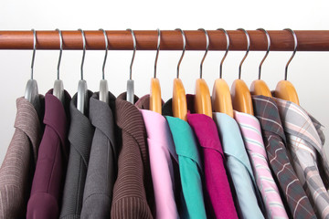 Different women's office classic jackets and shirts hang on a hanger for storing clothes. The choice of style of fashionable clothes