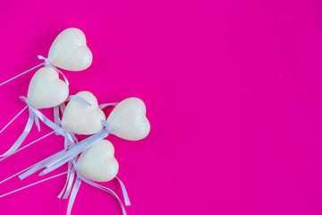 White hearts on a stick with a ribbon, pink background. Valentine's Day. Top view, flat lay, copy space