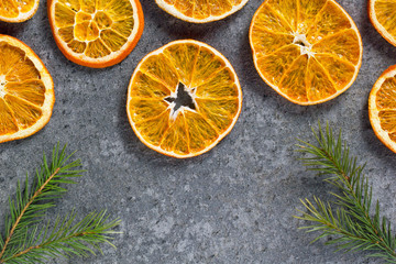 Christmas background mockup top view with copy space. Fir tree branches and dry oranges on dark background flat lay. Winter holiday frame. New Year's composition. Mockup sliced oranges with a crust.