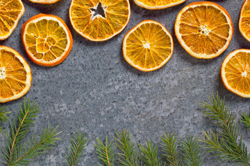 Fototapeta na wymiar Christmas background mockup top view with copy space. Fir tree branches and dry oranges on dark background flat lay. Winter holiday frame. New Year's composition. Mockup sliced oranges with a crust.