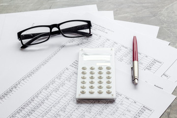 Taxes calculation concept. Financial documents, calculator, glasses on grey background