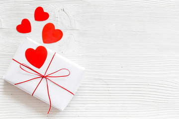 Valentine's Day gift. Present box near paper hearts on white wooden background top-down copy space