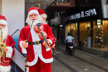 Panaji, Goa, India - December 15, 2019: Big Toy Santas plays musical instruments. Streets of the...