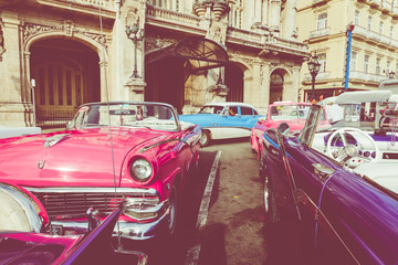 Fototapeta na wymiar Vintage colored classic american cars front of the Galician Palace on Prado Street in Havana, Cuba.