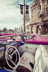 Vintage colored classic american cars front of the Galician Palace on Prado Street in Havana, Cuba.