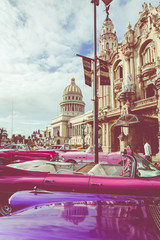 Vintage colored classic american cars front of the Galician Palace on Prado Street in Havana, Cuba.
