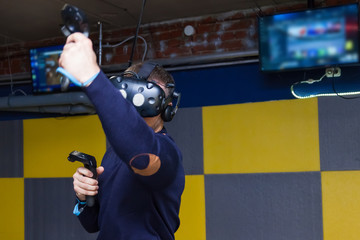 The guy plays a fight connected to virtual reality in a helmet with remote controls. Modern technologies in computer games and entertainment. Cyberspace and virtuality.