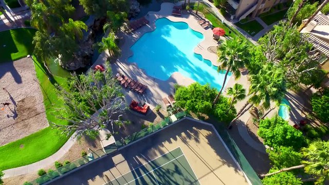 Aerial drone photography looking down on a pool and sand volleyball courts.
