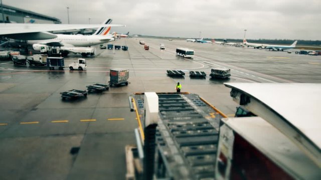 Unknown parked airliners and utility vehicles at international airport. Loading flight supplies to the commercial plane