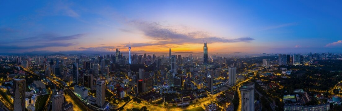 Panoramic drone aerial view of sunrise at Kuala Lumpur city skyline. Image may contain noise due to low light and high ISO setting. 