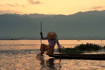 A fisherman on the boat using coop to catch fishes on the Inle lake in the morning, Myanmar