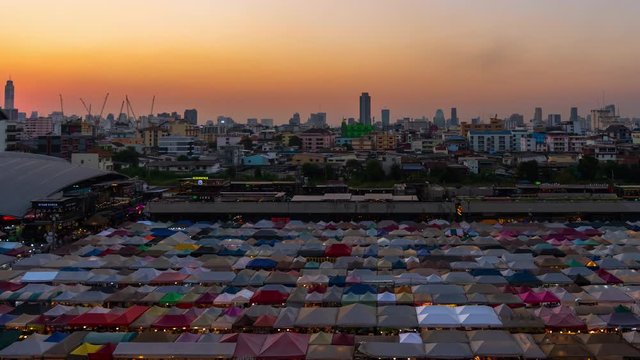 day to night time lapse of Train Night Market Ratchada (Talad Rot Fai) at night in Bangkok, Thailand