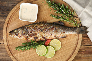 Delicious grilled fish served on wooden table, top view