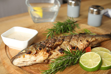 Delicious grilled fish with lime on wooden board, closeup