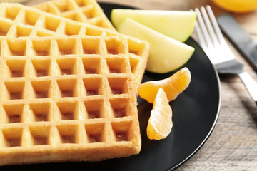 Waffles with fruits served on wooden table, closeup. Delicious breakfast
