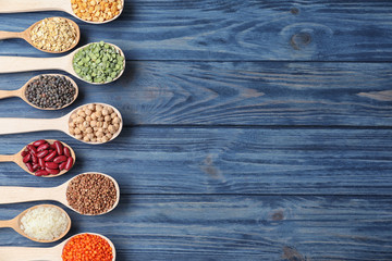 Flat lay composition with different types of legumes and cereals on blue wooden table, space for text. Organic grains