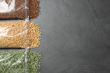 Flat lay composition with different types of legumes and cereals on dark grey table, space for text. Organic grains