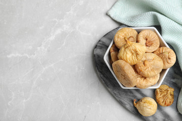 Tasty dried figs in bowl on light grey table, top view. Space for text