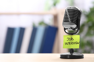 Retro microphone and reminder note with words JOB INTERVIEW on table indoors, space for text