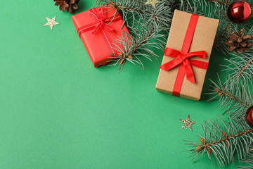 Flat lay composition with decorated fir branches and gifts on green background, space for text. Winter holidays