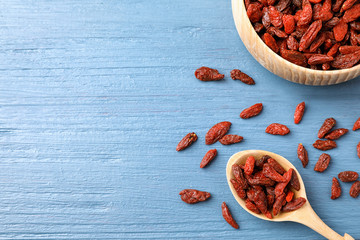 Dried goji berries on blue wooden table, flat lay. Space for text