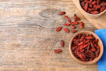 Dried goji berries on wooden table, flat lay. Space for text