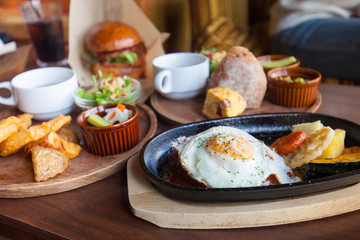 Homemade fried egg with potato, Hamburger with Egg Lettuce and Tomato. hamburger beef steak grill bread with rocket salad tomato, egg black pepper seed on wooden plate, selective focus. chips and tea