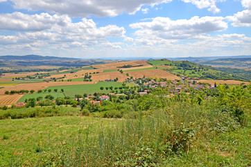 Fototapeta na wymiar Beautiful rural landscape with blue sky, spectacular clouds and wheat fields in Auvergne region in France