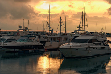 Fototapeta na wymiar modern small boats and sailboats are parked in a quiet harbor in the seaport of Sochi on a rainy evening