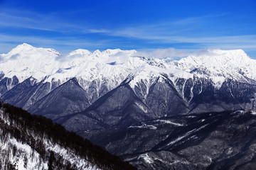 Winter mountains and blue sky with beautiful clouds and their shadows fall on peaks of Caucasus mountain range.