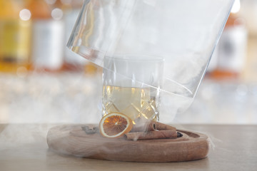 Hazy Whiskey Cocktail, A glass of smoked whiskey served with a slice of dry orange and cinamon stick