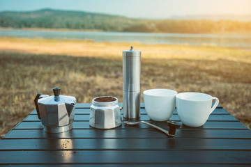 Ground coffee and moka pot coffee maker, Outdoor moka coffee set on picnic table on the morning.