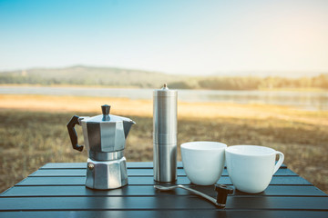 Ground coffee and moka pot coffee maker, Outdoor moka coffee set on picnic table on the morning.