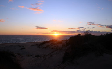 Fototapeta na wymiar Sunrise at the beach with dunes and clear sky