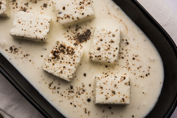 Paneer Dum Kali Mirch / Kalimirch, prepared in a white creamy gravy and black pepper powder sprinkled over it. served in a bowl. Selective focus