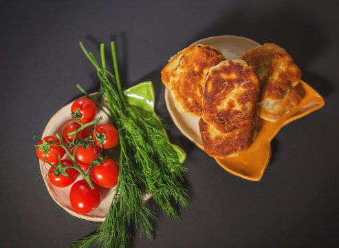 red cherry tomatoes with dill and belyash on a black background
