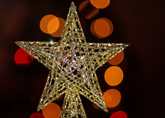 Gold Christmas star close up with orange blurred bokeh