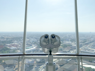 binoculars for tourist inside the building and city background.