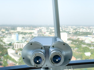 binoculars for tourist inside the building and city background.