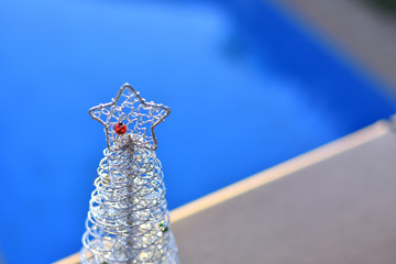 Small silver Christmas tree with red detail on the star on blue background