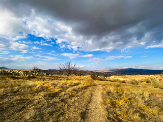 View of a valley filled with ancient rock formations. Blue sky, white clouds. Cappadocia, Turkey. 5 november 2019
