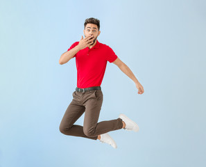 Fototapeta na wymiar Shocked jumping young man on color background