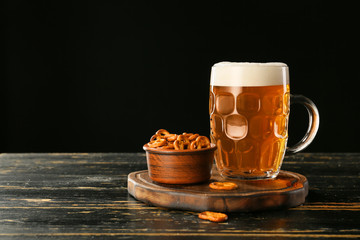 Mug of fresh beer and snack on wooden table